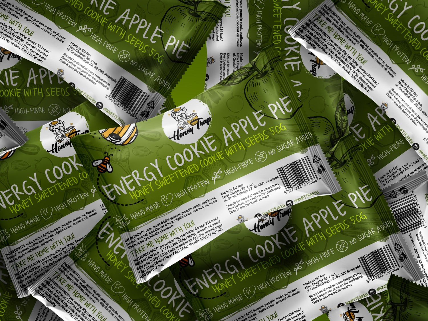 Zbliżenie na zielone opakowania ciastek energetycznych Honey Trap z jabłkiem i nasionami, ułożone warstwami, z widocznymi informacjami o składzie i wartościach odżywczych.
