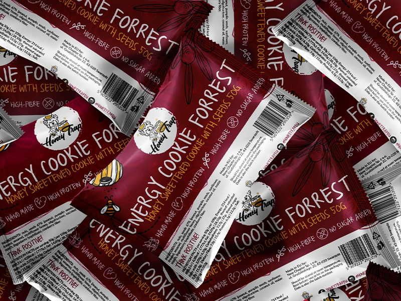 Stos opakowań batonów energetycznych Honey Trap z informacjami o składzie i wartościach odżywczych, z wyraźnym logo marki i hasłem 'Think Positive!'