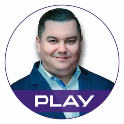 Portret uśmiechniętego mężczyzny w niebieskiej marynarce i koszuli, umieszczony w okręgu z logo 'PLAY' na fioletowym tle.