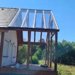 Szklana konstrukcja dobudowana do domu jednorodzinnego w Międzychodzie, widok z zewnątrz, widoczne drewniane elementy konstrukcyjne i szklane panele dachowe, częściowo zamontowane.