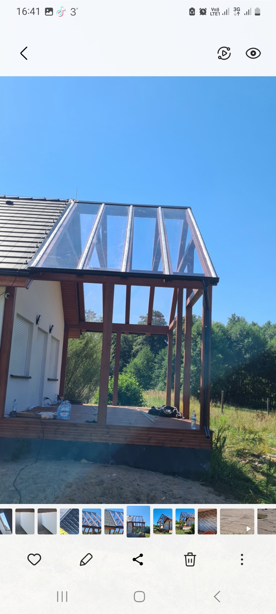 Szklana konstrukcja dobudowana do domu jednorodzinnego w Międzychodzie, widok z zewnątrz, widoczne drewniane elementy konstrukcyjne i szklane panele dachowe, częściowo zamontowane.