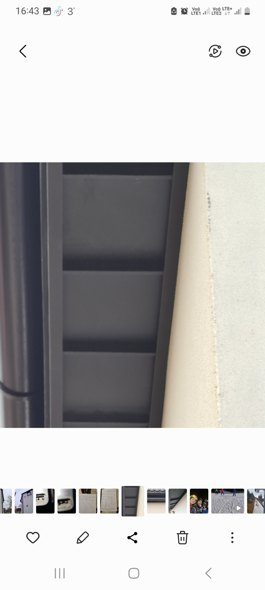 Fragment podbitki dachowej w kolorze grafitowym, widoczny od spodu, przylegający do ściany budynku.