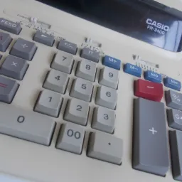 Kalkulator biurowy Casio FR-3400 z rolką papieru, widoczne przyciski z cyframi i funkcjami matematycznymi, ustawiony pod kątem na jasnym tle.