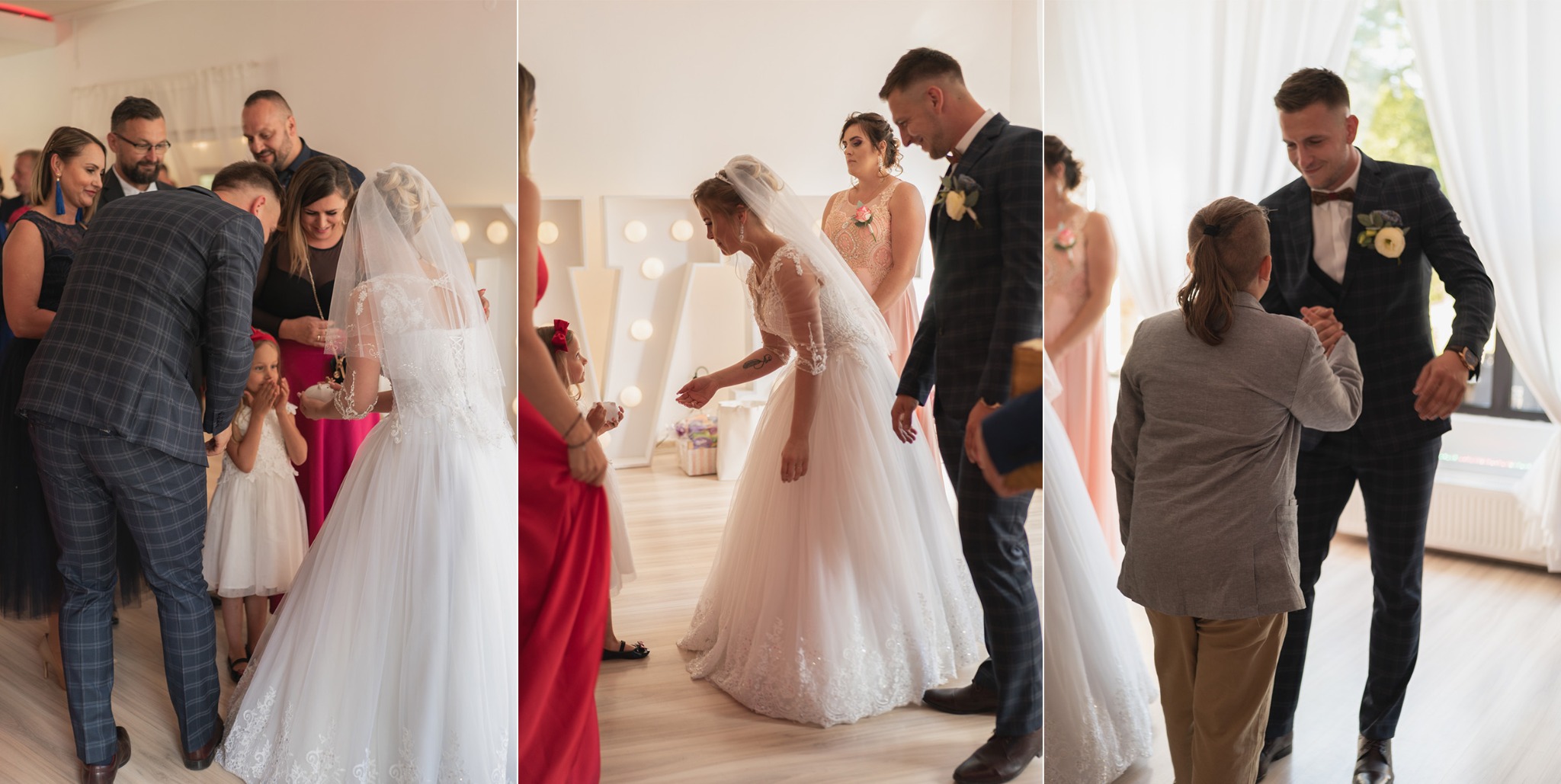 Panna młoda w białej sukni z welonem przyjmuje życzenia od gości weselnych, w tle dekoracyjne litery podświetlone żarówkami.