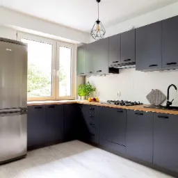 Nowoczesna kuchnia w odcieniach szarości z drewnianym blatem, srebrną lodówką i geometryczną lampą wiszącą.