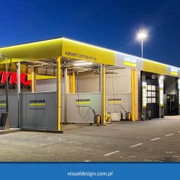 VISUAL Sp. z o.o. - Nowoczesna, żółto-szara stacja mycia Kärcher Centrum Mycia oświetlona wieczornym światłem. Widoczny automat do mycia i osoba przechodząca obok stanowisk.