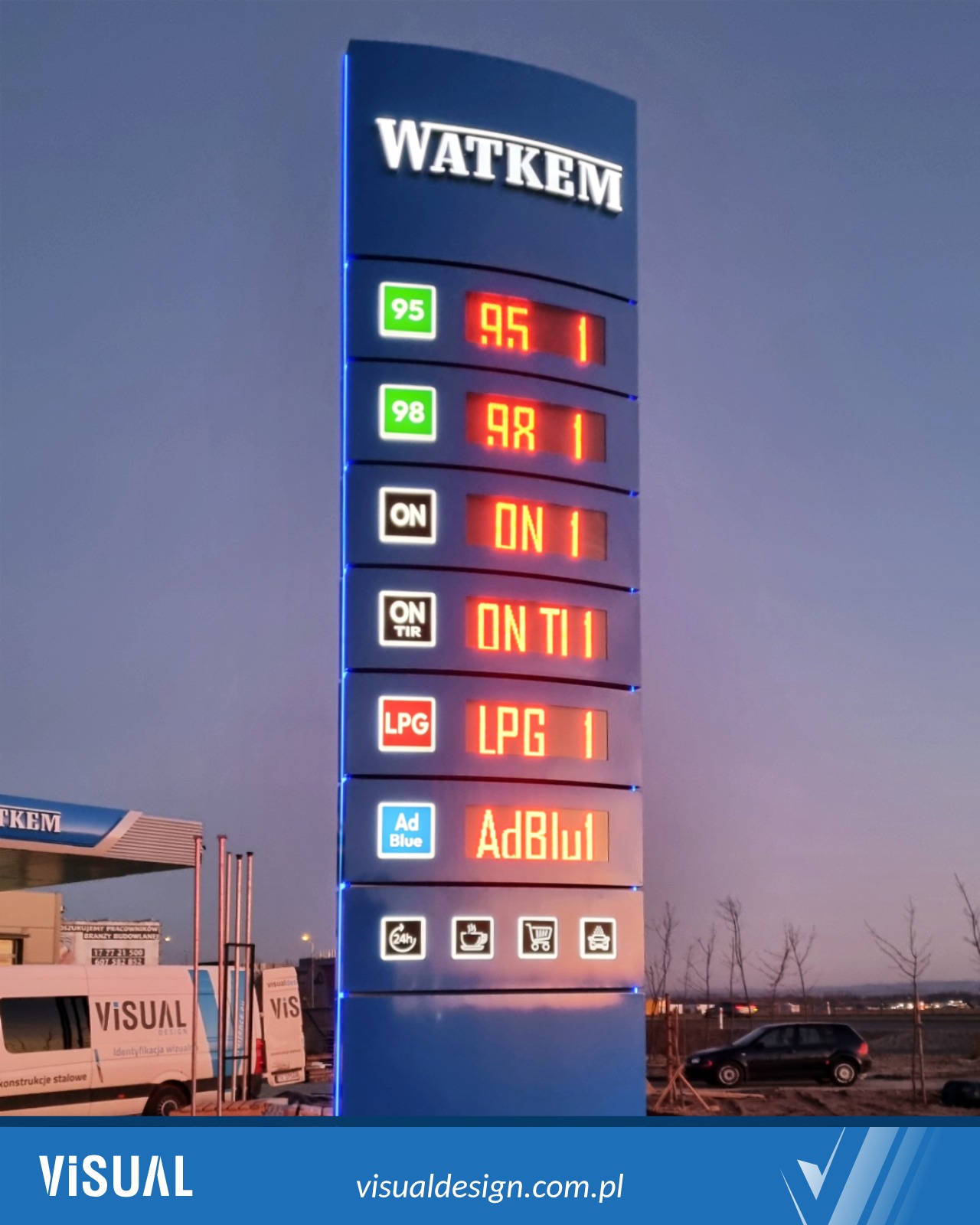 Pylon cenowy stacji paliw WATKEM z wyświetlaczami LED cen paliw i AdBlue, widoczny z daleka, z logo firmy i ofertą. W tle budynek stacji i pojazd.