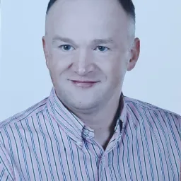 Portret mężczyzny w różowo-białej koszuli w paski z logo Polo Ralph Lauren, uśmiechniętego na białym tle.