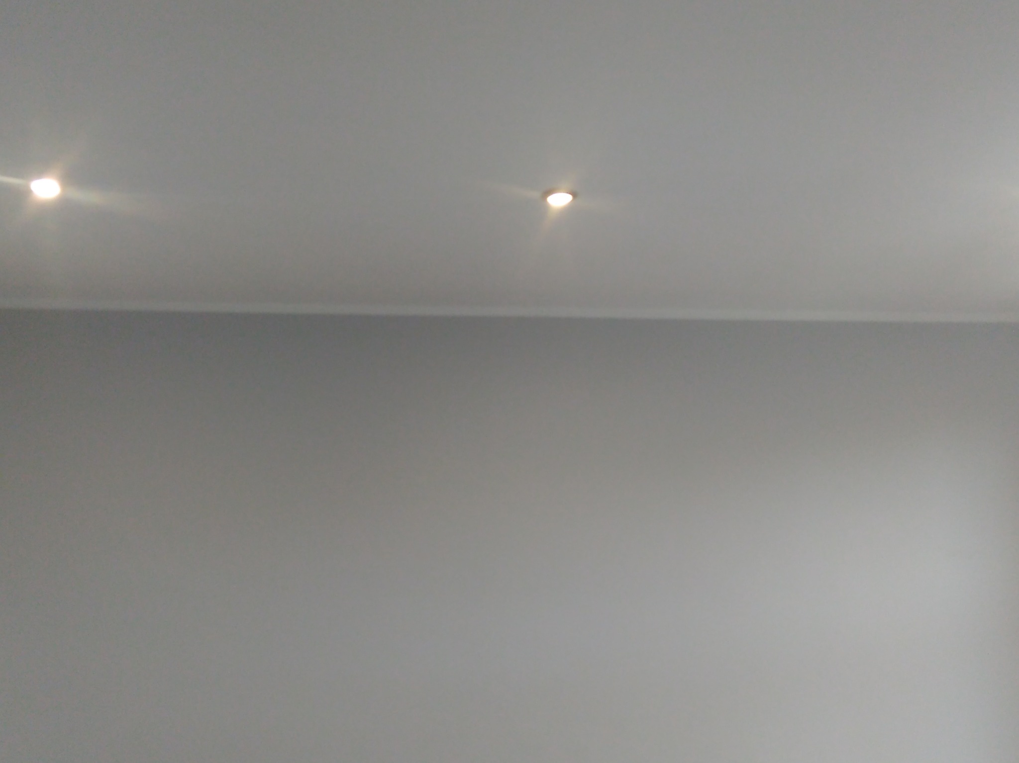 Szara ściana i sufit z dwoma punktowymi lampami LED, widok z dołu.