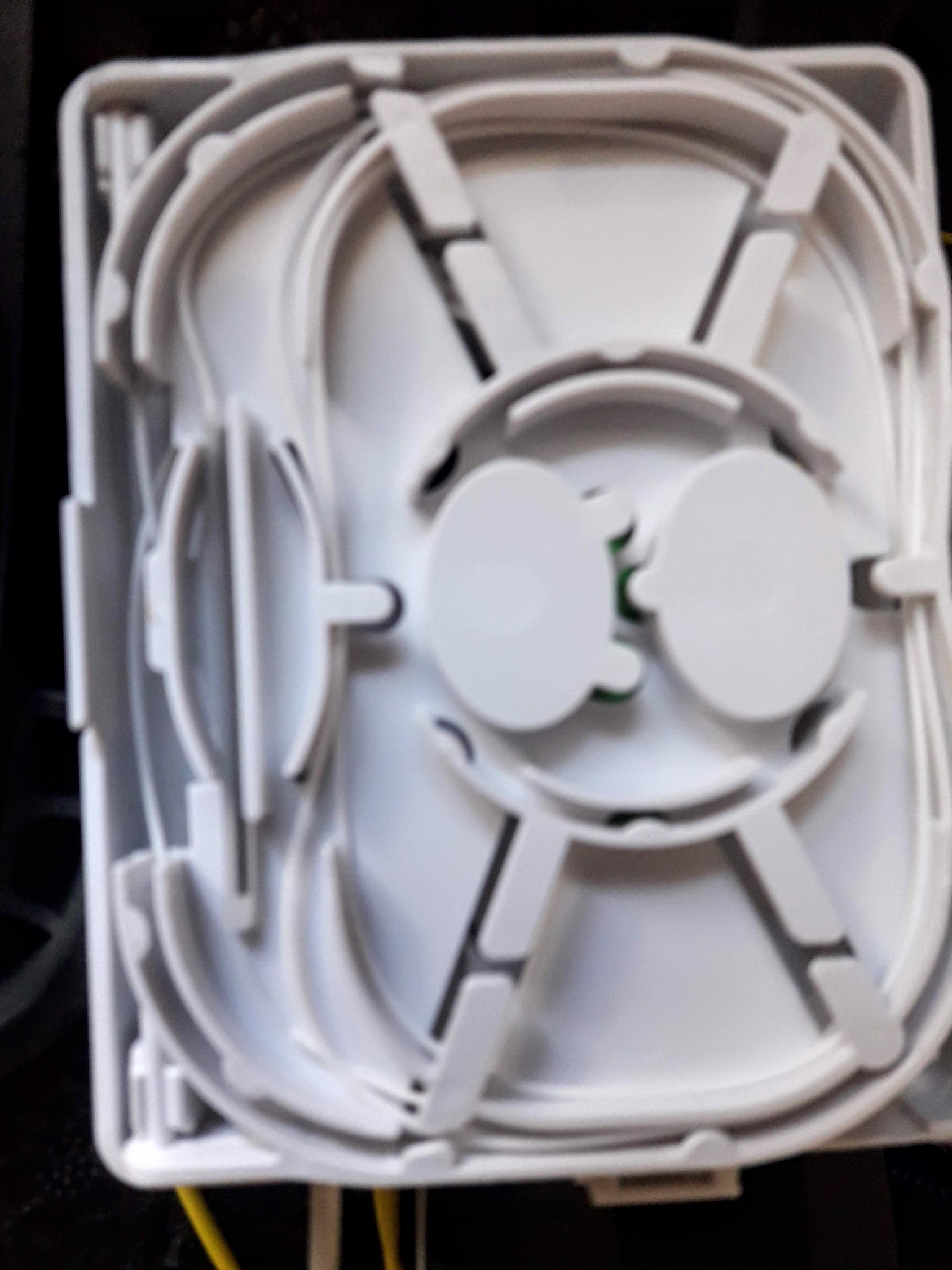 Otwarta, biała kaseta światłowodowa z widocznymi elementami do prowadzenia i łączenia włókien światłowodowych, z żółtymi kablami w tle.