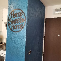 Garant-BUD - Dekoracyjna ściana w odcieniach błękitu i granatu z efektem strukturalnym, ozdobiona metalowym napisem 'Home Sweet Home' w mieszkaniu w Warszawie.
