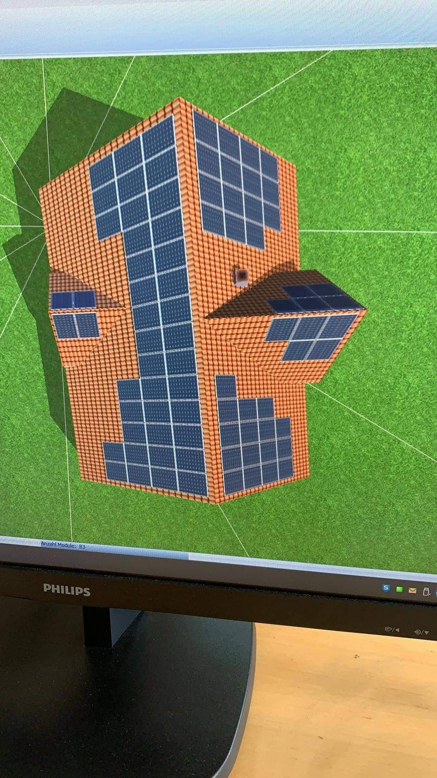 Wizualizacja 3D domu z panelami słonecznymi na dachu i ścianach, widok z góry, wyświetlana na ekranie monitora Philips.