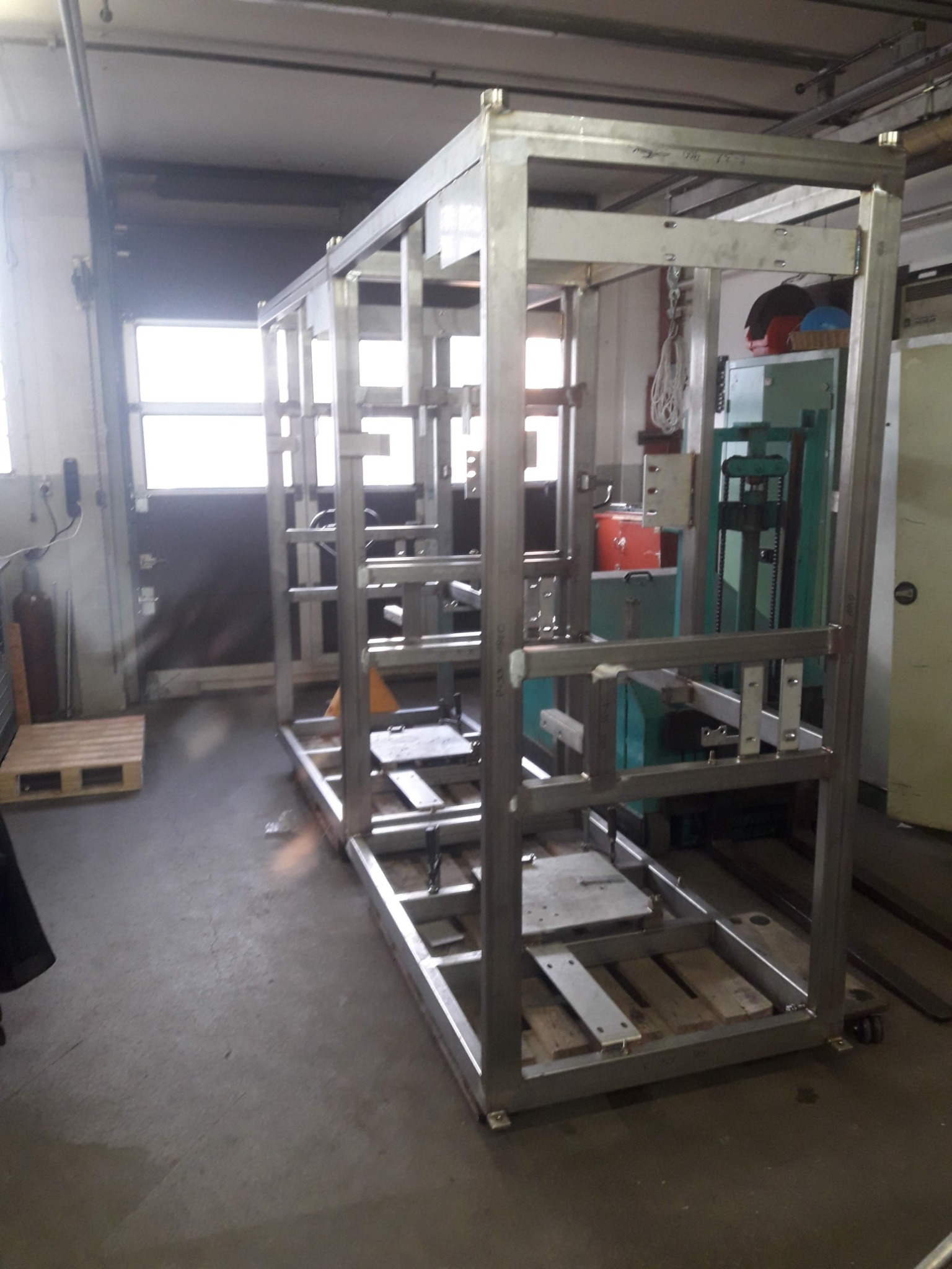 Stalowa konstrukcja szkieletowa na kółkach, prawdopodobnie w hali produkcyjnej, widoczne spawy na łączeniach profili.