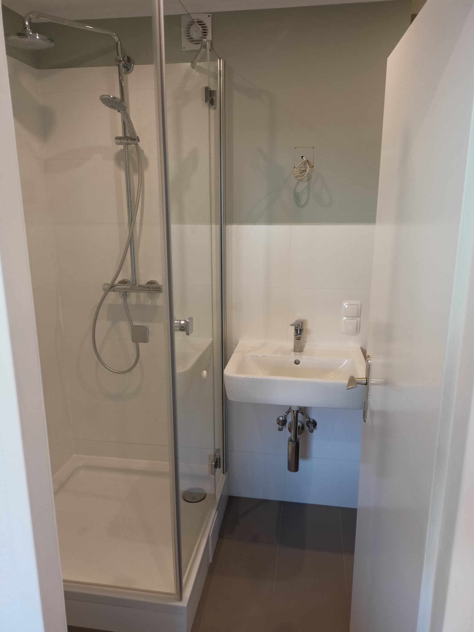 Nowoczesna, minimalistyczna łazienka w Słubicach z kabiną prysznicową typu walk-in i umywalką nablatową, wykończona białymi płytkami i szarymi ścianami.