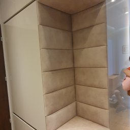 DREAMWOOD SYSTEM Przemysław Pachuta - Beżowa szafa wnękowa z panelem tapicerowanym tworzącym siedzisko w rogu, widok z boku na fragment wnętrza.