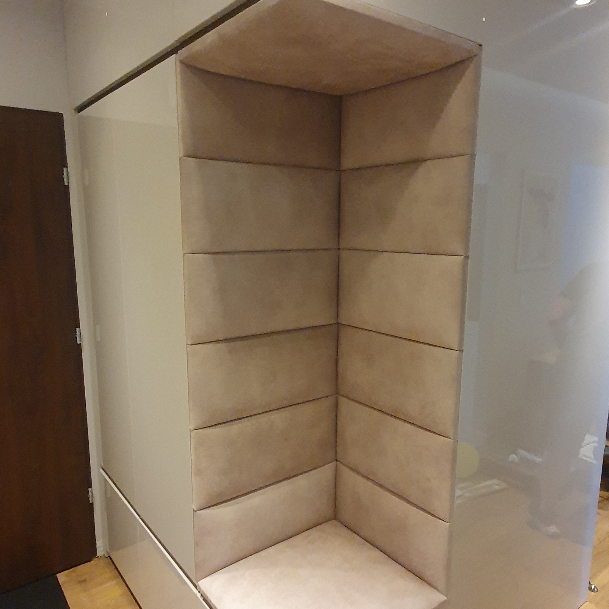 Narożna, tapicerowana wnęka z siedziskiem w szafie wnękowej, widoczna z bliska, z jasnymi panelami i minimalistycznym designem.