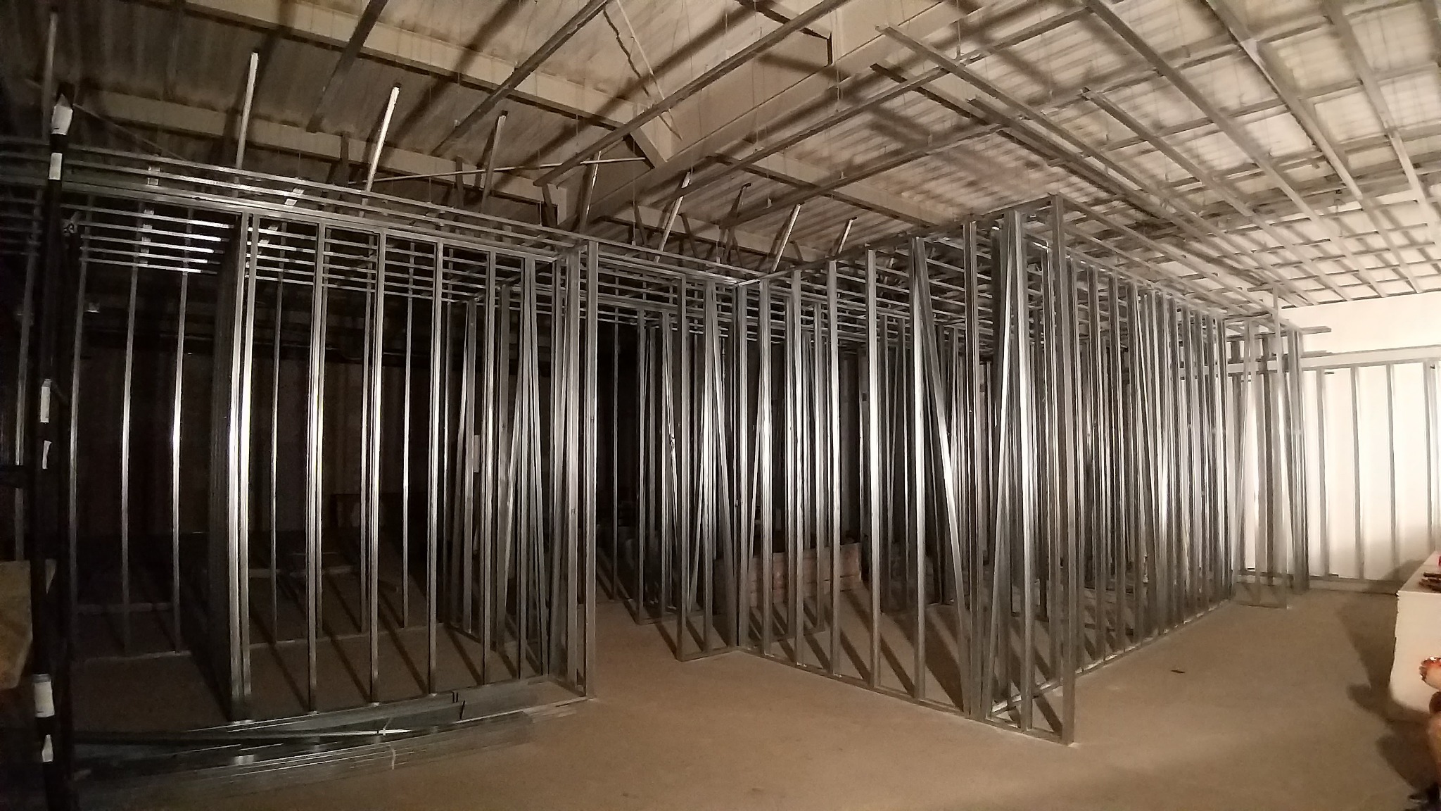 Stelaż z profili metalowych przygotowany do montażu płyt gipsowo-kartonowych, widoczne profile sufitowe i ścienne, surowy stan wykończenia.