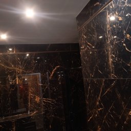 Sebastian Napierała - Ściany i sufit wyłożone czarnym marmurem z wyraźnym złotym użyleniem, oświetlone punktowymi lampami, tworzące luksusowe wnętrze.