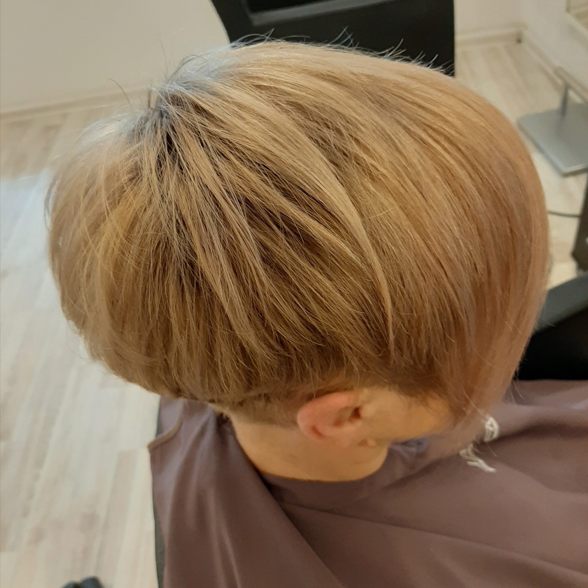 Blond włosy ostrzyżone na krótko z widocznym podgoleniem na karku, widok z góry.