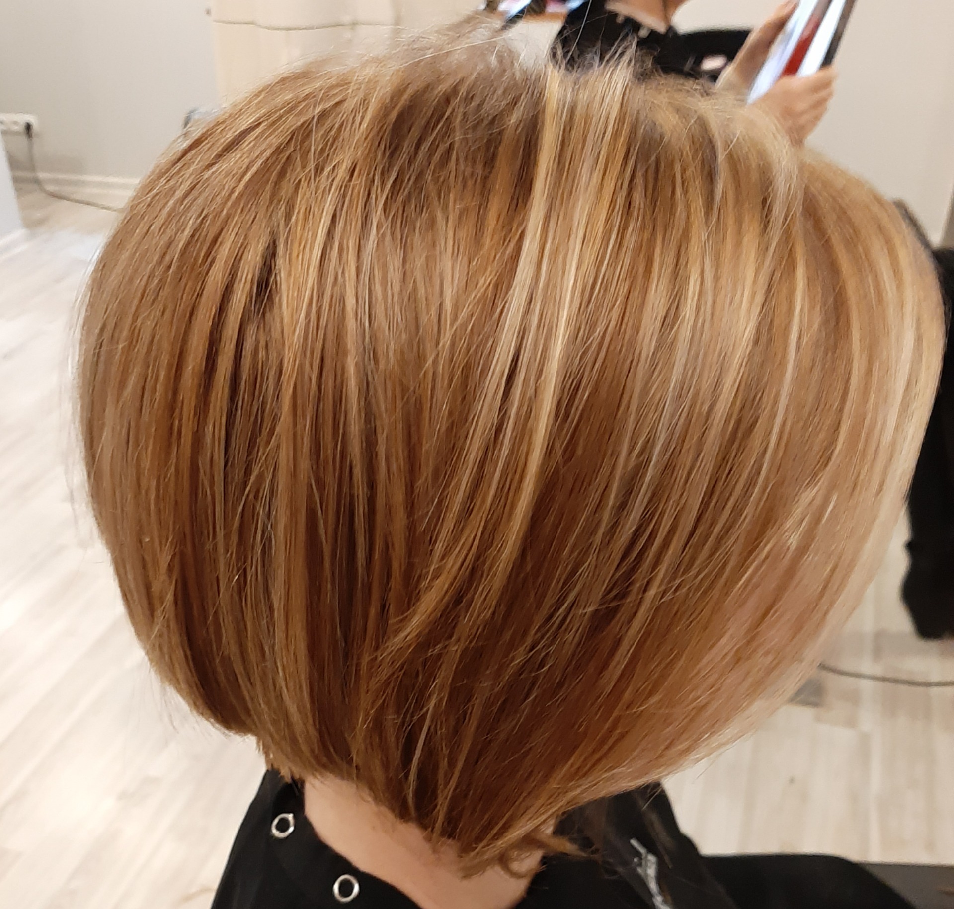 Krótkie, wycieniowane włosy w odcieniach blondu i miedzi, z widocznymi jaśniejszymi pasemkami, stylizowane na okrągło, widok z tyłu.