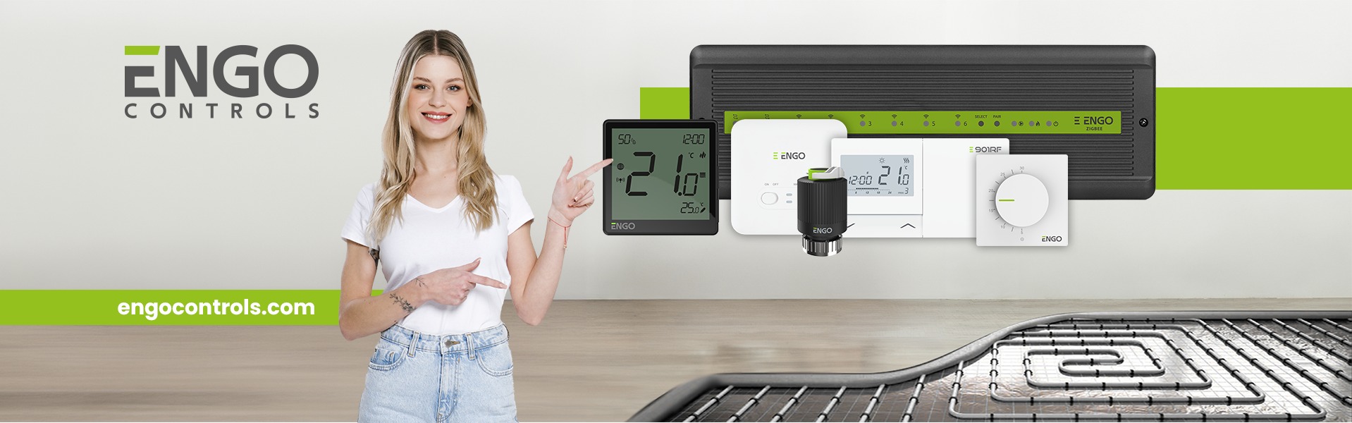 Kobieta prezentuje system sterowania ogrzewaniem podłogowym marki ENGO, z widocznymi elementami instalacji i regulatorami temperatury.