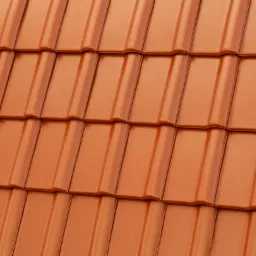 Pomarańczowe dachówki ceramiczne ułożone w rzędach, widok z bliska, podkreślona faktura i połysk materiału.