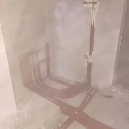 Surowe wnętrze w trakcie prac instalacyjnych: czerwone rury rozprowadzone po podłodze i ścianach, zabezpieczone pianką montażową, widoczne przyłącza.