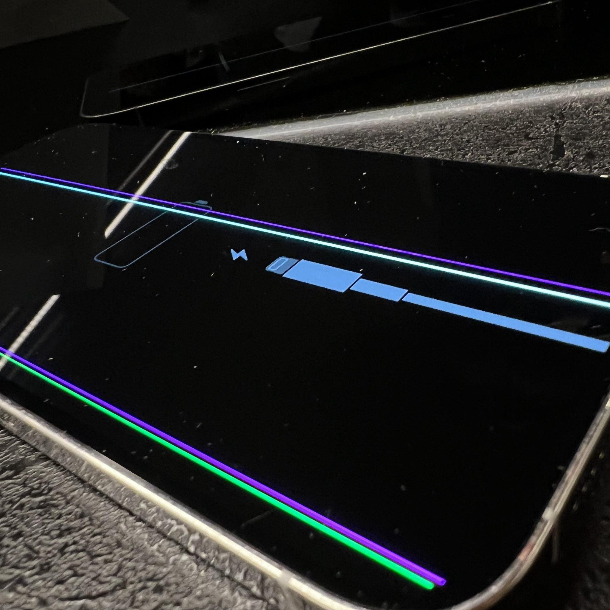 Wyświetlacz laptopa z widocznym paskiem postępu ładowania baterii oraz kolorowymi liniami diagnostycznymi na czarnym tle.