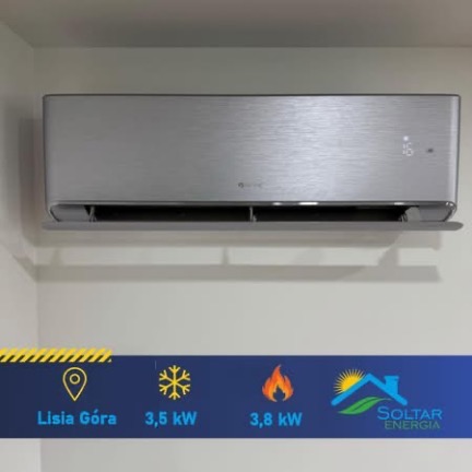 Elegancki, srebrny klimatyzator ścienny z wyświetlaczem temperatury, zamontowany w rogu pomieszczenia. Pod spodem grafika z parametrami i logo firmy.