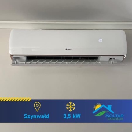 Biały klimatyzator marki Gree zamontowany na ścianie, z wyświetlaczem temperatury 30 stopni Celsjusza. Widoczny panel informacyjny z nazwą miejscowości i parametrami urządzenia.