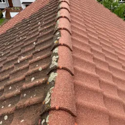 Częściowo wyczyszczony dach z czerwonej dachówki ceramicznej, widoczna różnica między brudną, porośniętą mchem i porostami powierzchnią a czystą, umytą częścią dachu. Dachówka karpiówka...