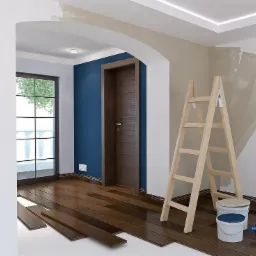 Wnętrze w trakcie prac wykończeniowych: panele podłogowe z ciemnego drewna układane na białym podłożu, drewniana drabina oparta o ścianę z widocznymi śladami malowania, niebieska ściana w tle...