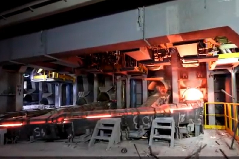 Wnętrze hali produkcyjnej z piecem hutniczym w trakcie remontu, widoczne stalowe elementy konstrukcyjne i schodki robocze.