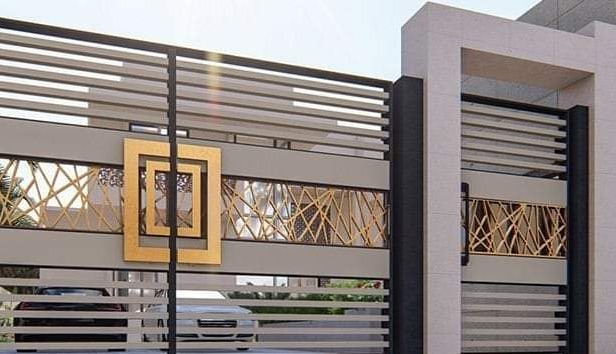 Nowoczesna brama wjazdowa z poziomymi panelami i złotym geometrycznym zdobieniem, widok z zewnątrz na podjazd z samochodami.