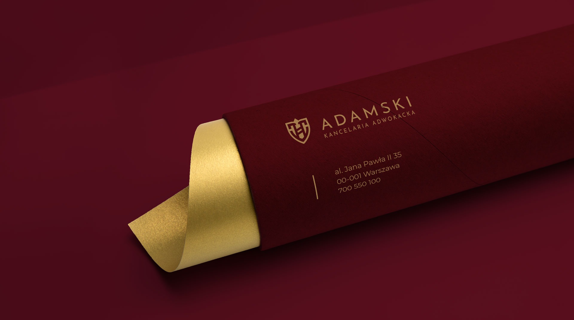 Elegancka wizytówka kancelarii adwokackiej Adamski w kolorze bordowym z elementami złota, prezentująca logo i dane kontaktowe