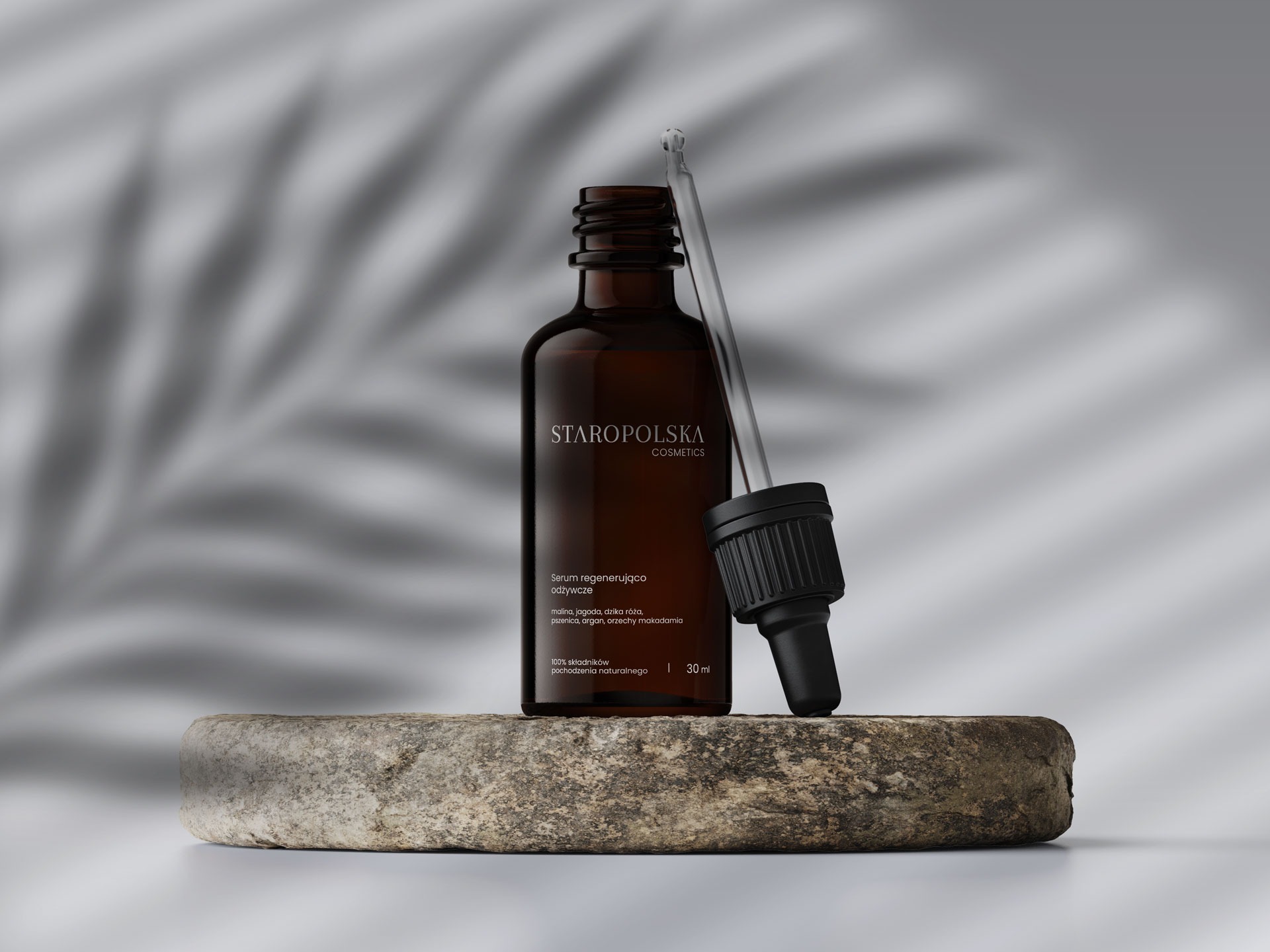 Butelka brązowego serum Staropolska Cosmetics z pipetą, umieszczona na szorstkim kamieniu na tle z cieniem liścia palmy.