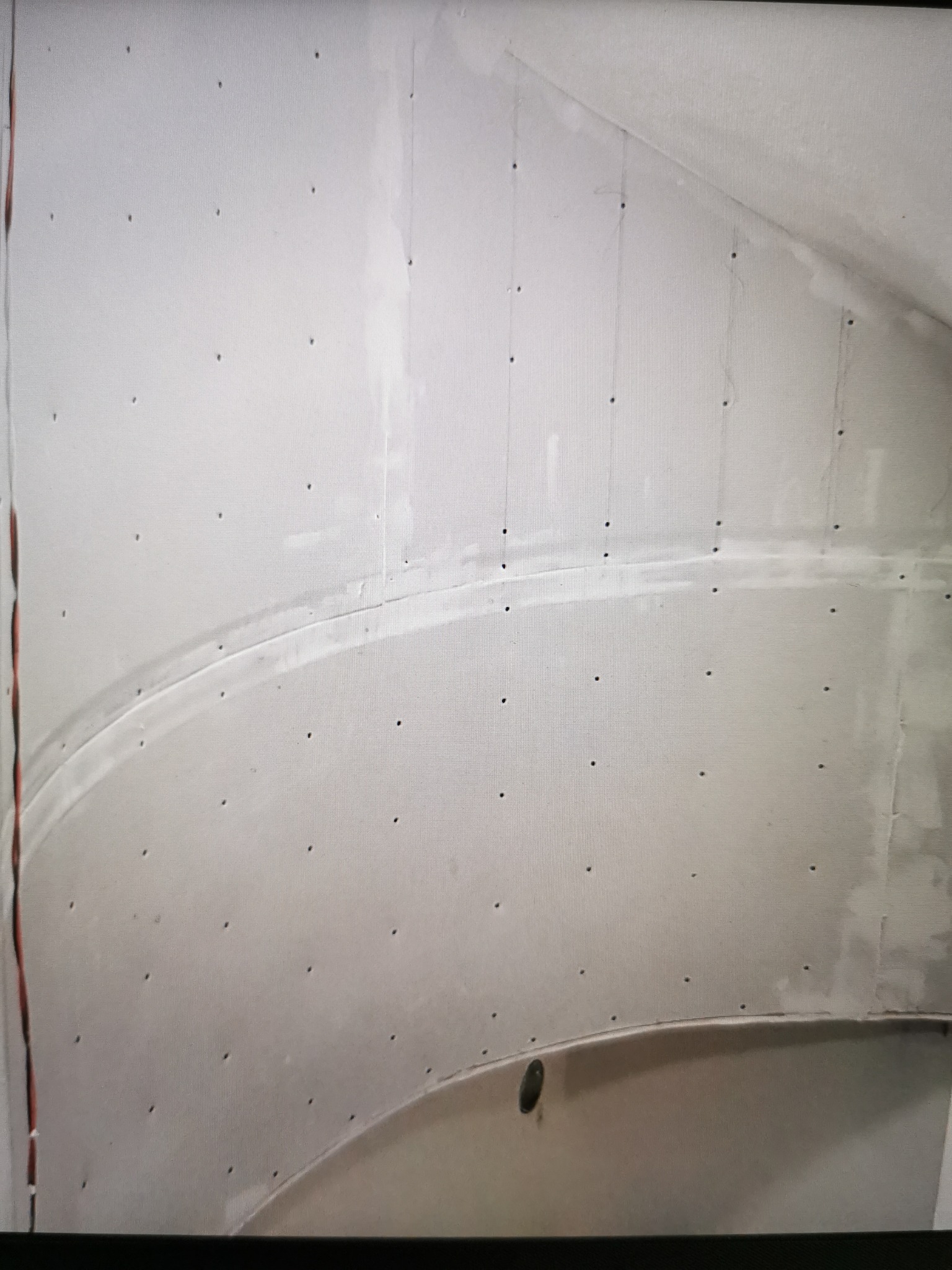 Zakrzywiona ściana z płyty karton gips, widoczne łączenia i ślady szpachlowania, przygotowana do dalszych prac wykończeniowych.