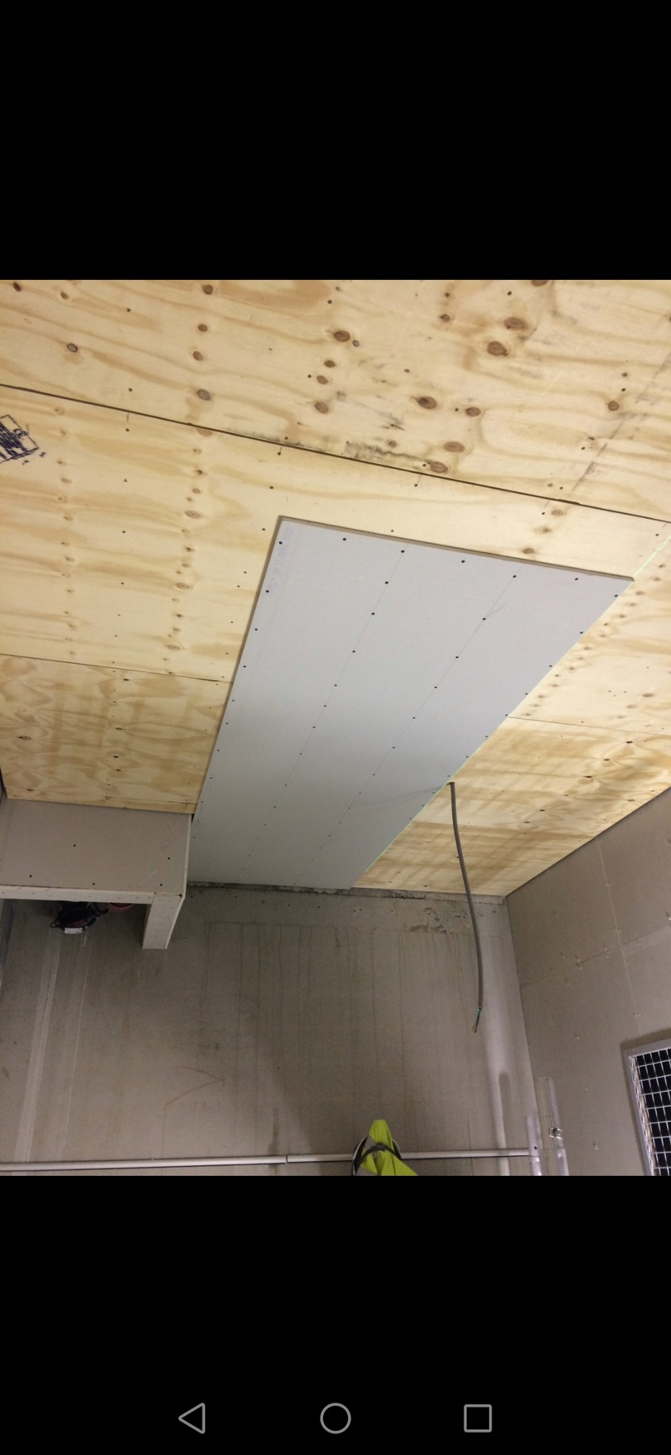 Montaż płyty karton gips na drewnianym suficie, widoczne ślady po wkrętach, wiszący kabel elektryczny i fragment ściany z widocznymi śladami po montażu.