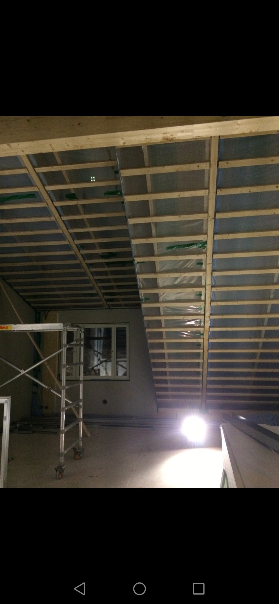 Stelaż drewniany poddasza przygotowany pod izolację i obłożenie płytami, widoczny fragment rusztowania i okno.