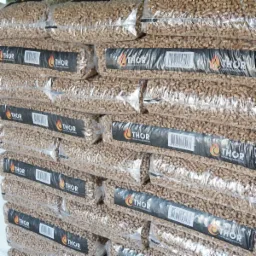 Stos przezroczystych worków z pelletem drzewnym, etykieta marki THOR z płomieniem i kodem kreskowym.