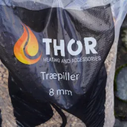 Worek z pelletem drzewnym marki THOR, widoczny fragment opakowania z płomieniem i napisem 'Træpiller 8 mm'.