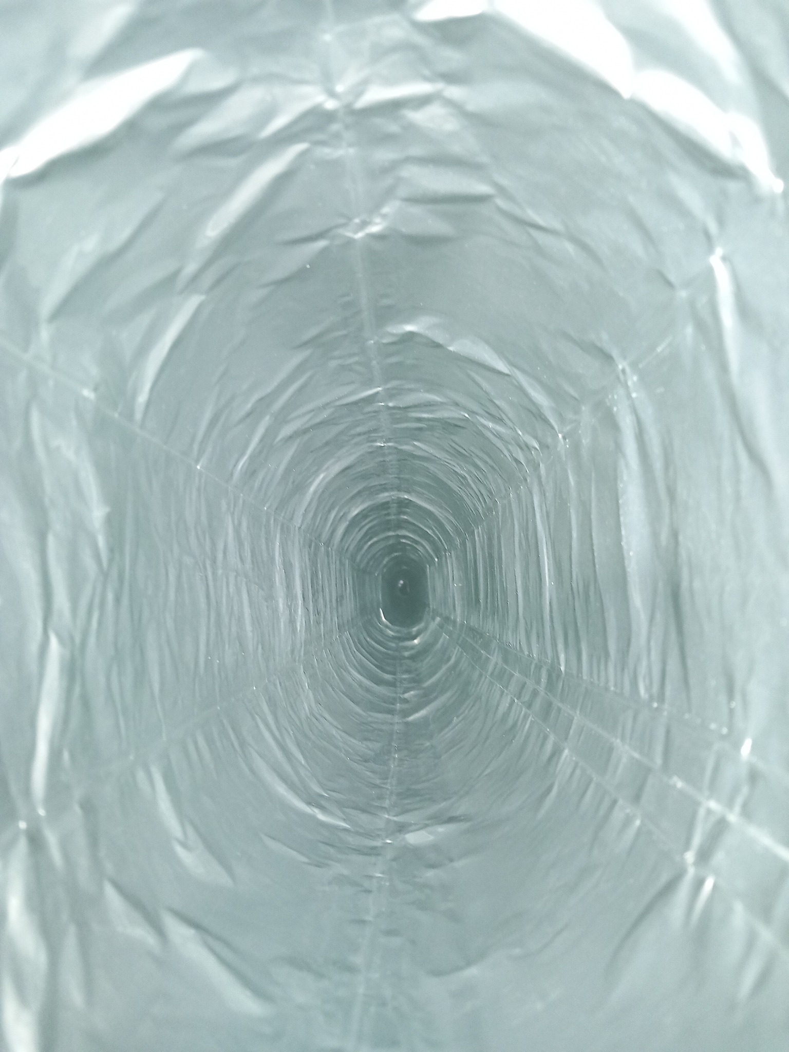 Wnętrze elastycznego przewodu kominowego z widocznymi fałdami i metalicznym połyskiem, perspektywa z wnętrza tunelu.