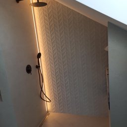 Marcin Bielecki - Nowoczesna kabina prysznicowa z czarną armaturą, podświetleniem LED i ścianą wyłożoną płytkami w jodełkę.