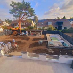 Krzysztof Wyszyński - Wykonywanie prac ziemnych i budowlanych na posesji: przygotowanie terenu pod ścieżki, budowa altany z kamienia i fundamentu pod basen z zieloną wodą, widoczne worki z materiałami budowlanymi...