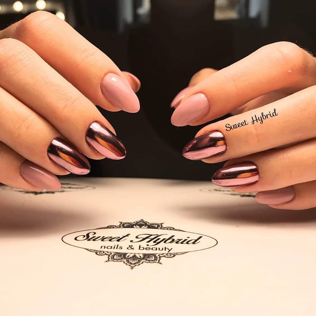 Dłonie z pomalowanymi paznokciami: trzy w kolorze pudrowego różu, dwa z efektem lustrzanej tafli w odcieniach różu i brązu, na tle blatu z logo salonu.