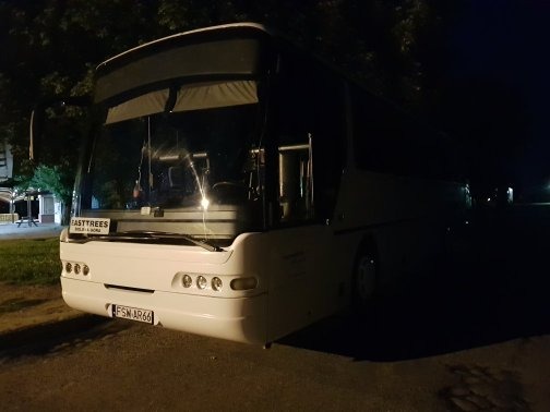 Biały bus marki Mercedes z widoczną tablicą rejestracyjną FSW AR66, zaparkowany nocą na oświetlonym placu.