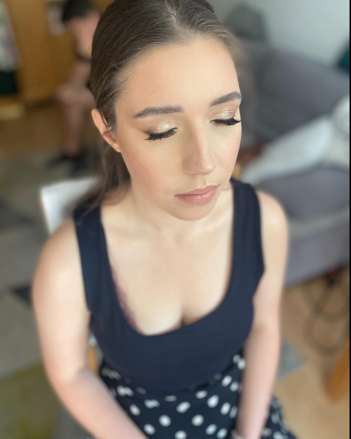 Portret kobiety z zamkniętymi oczami, prezentującej delikatny, złoty cień na powiekach, podkreślone rzęsy i subtelny makijaż ust w odcieniu nude.