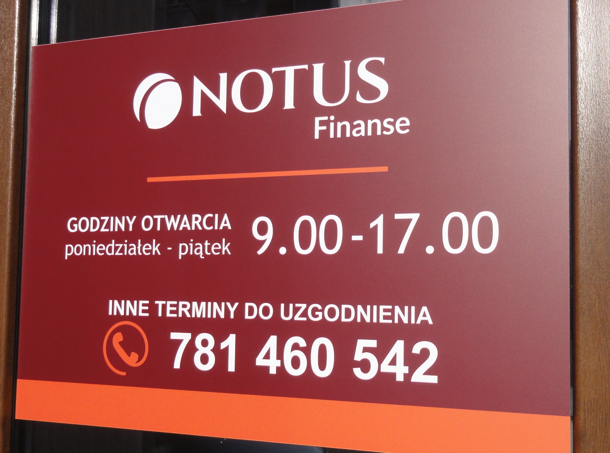 Tablica informacyjna z logo Notus Finanse, godzinami otwarcia od 9:00 do 17:00 od poniedziałku do piątku oraz numerem telefonu kontaktowego.
