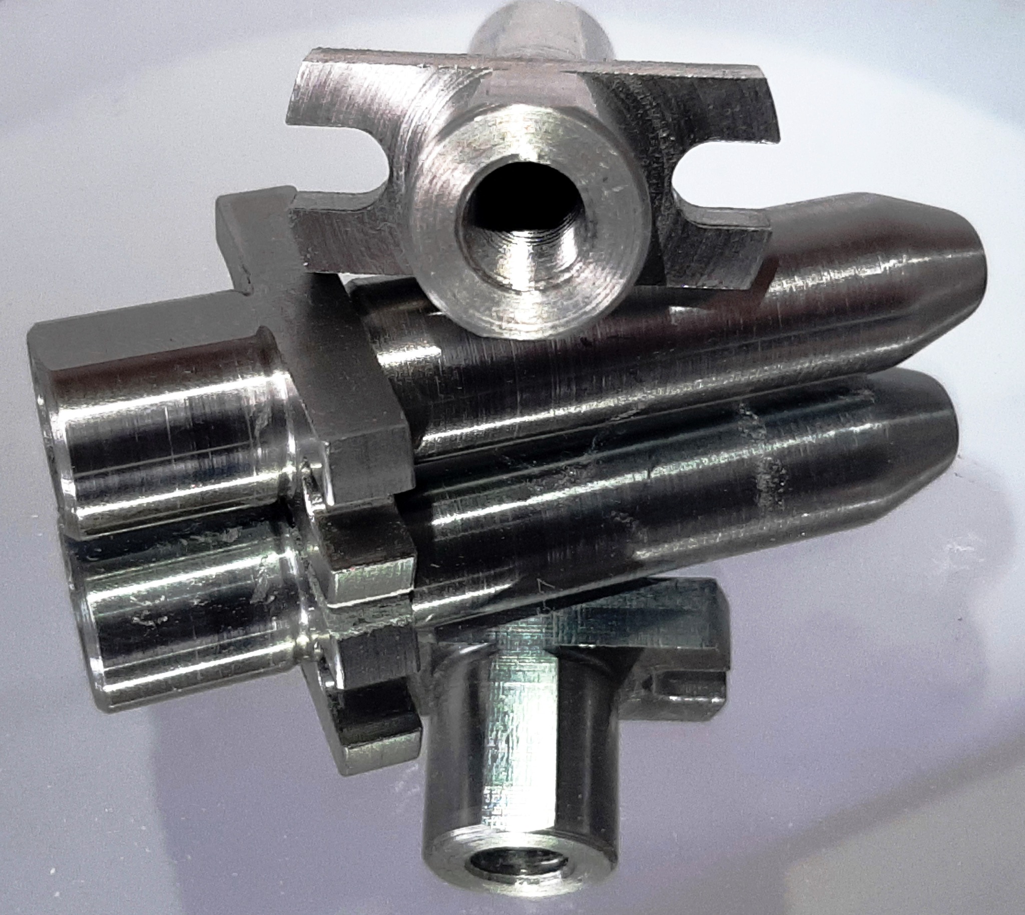 Precyzyjnie wykonany, metalowy element z gwintowanym otworem, obrobiony w Banská Bystrica, leżący na lustrzanej powierzchni.