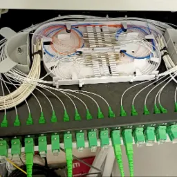 Panel krosowniczy światłowodowy z zielonymi złączami, uporządkowane kable wewnątrz obudowy, widoczne numery portów od 1 do 23.